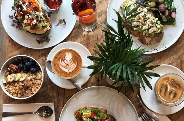 Aerial image of a table layout at Salt the Radish including coffee, granola, avocado toast and a plant in the centre.