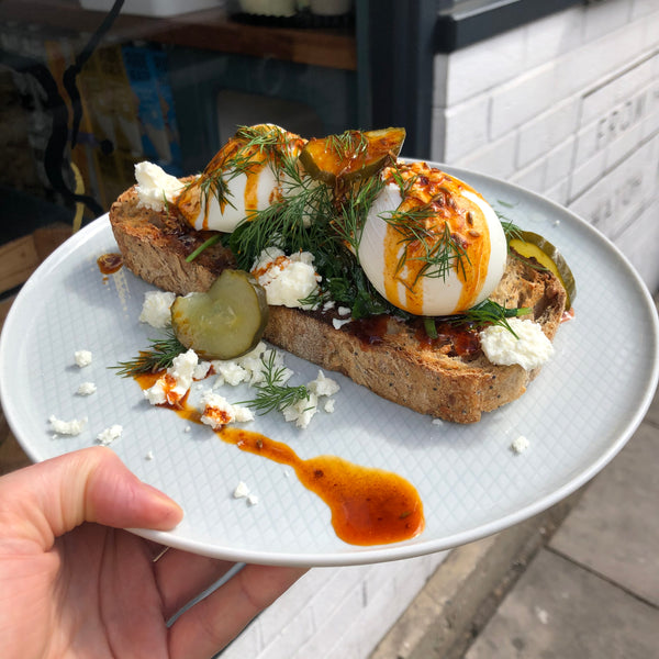 Poached eggs on toast with feta, dill, pickles and cumin oil.