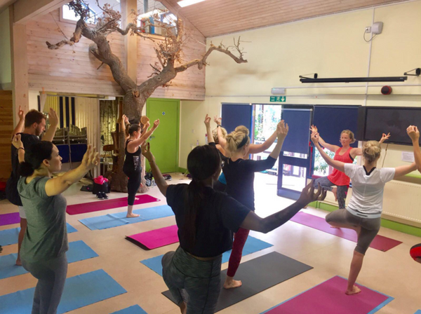 A group of people doing yoga in a large open room for an outside catering event.