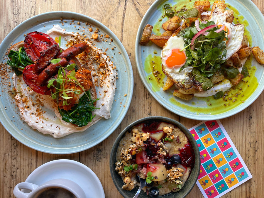 Flat lay with coffee, porridge, a potato and egg brunch dish and a chorizo, tomato and spinach brunch dish on toast.