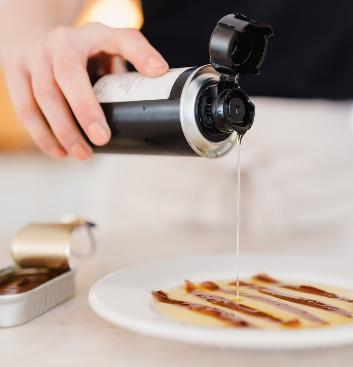 Pouring olive oil over anchovies.