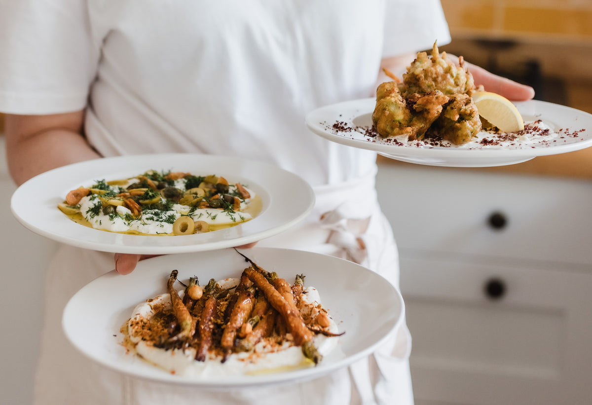 Chef carrying three plates of food.