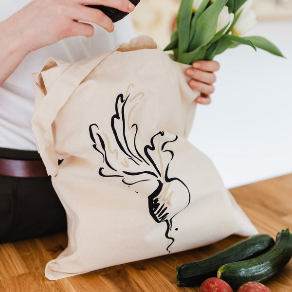 Radish tote bag being loaded with vegetables and flowers.