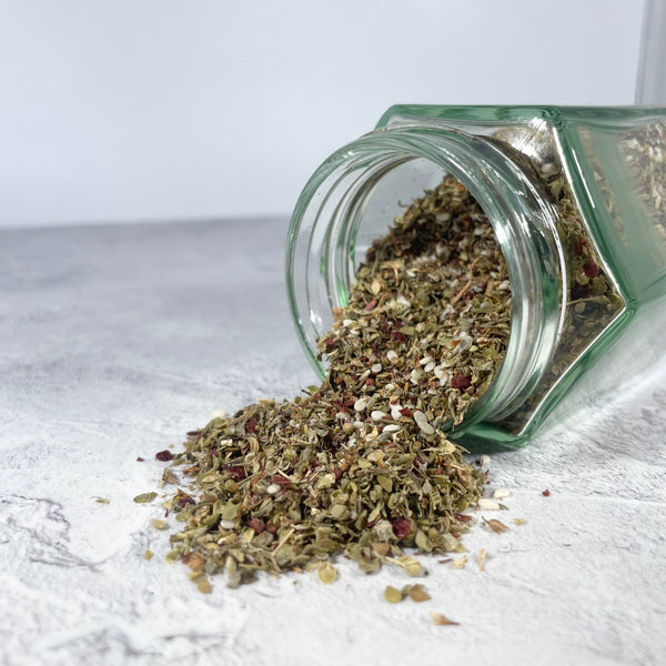 Glass jar on it's side with za'atar spilling out.