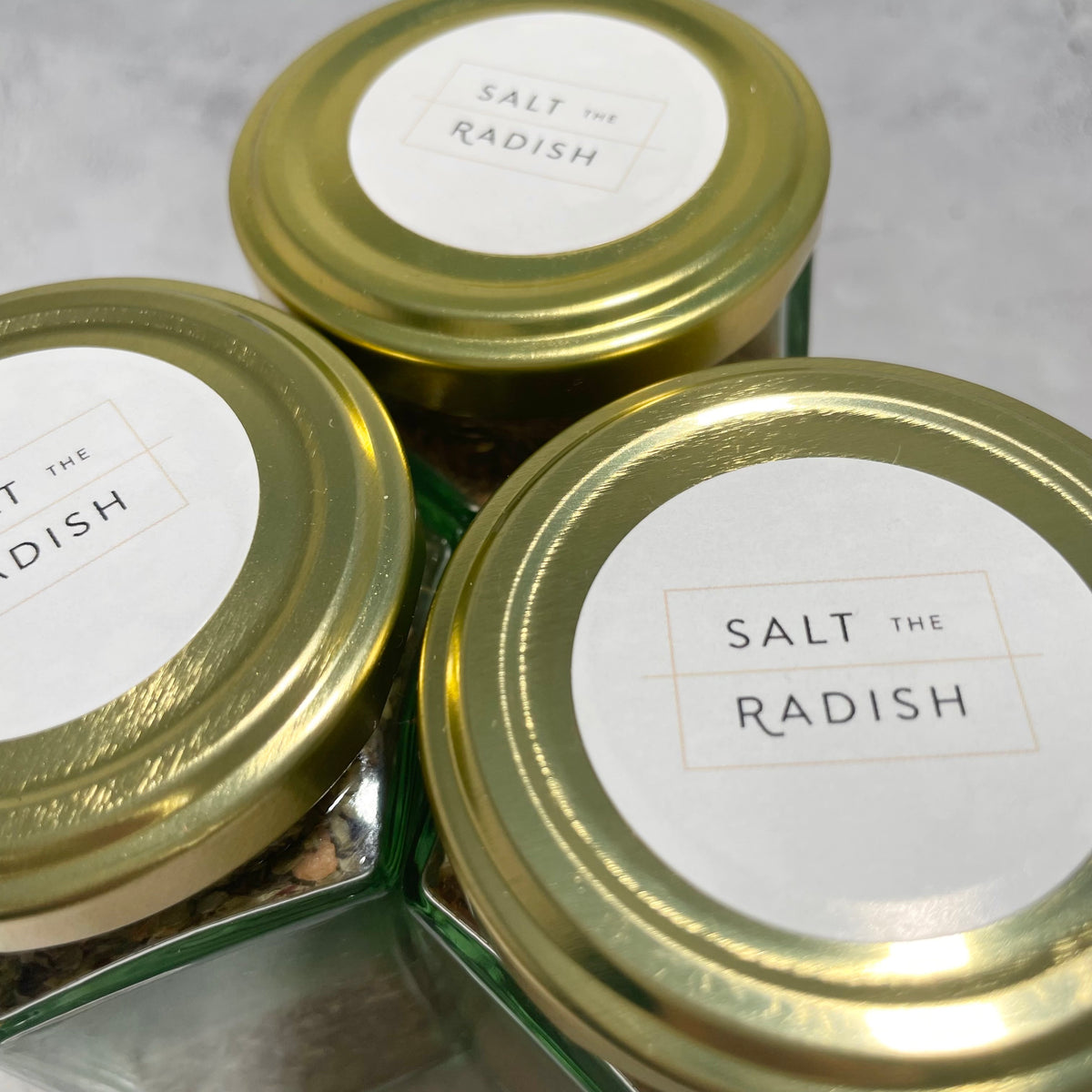 Top view of three spice jars next to each other showing the Salt the Radish logo on a sticker.